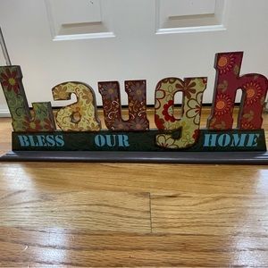 “Laugh (Bless Our Home)” wooden decorative item.
